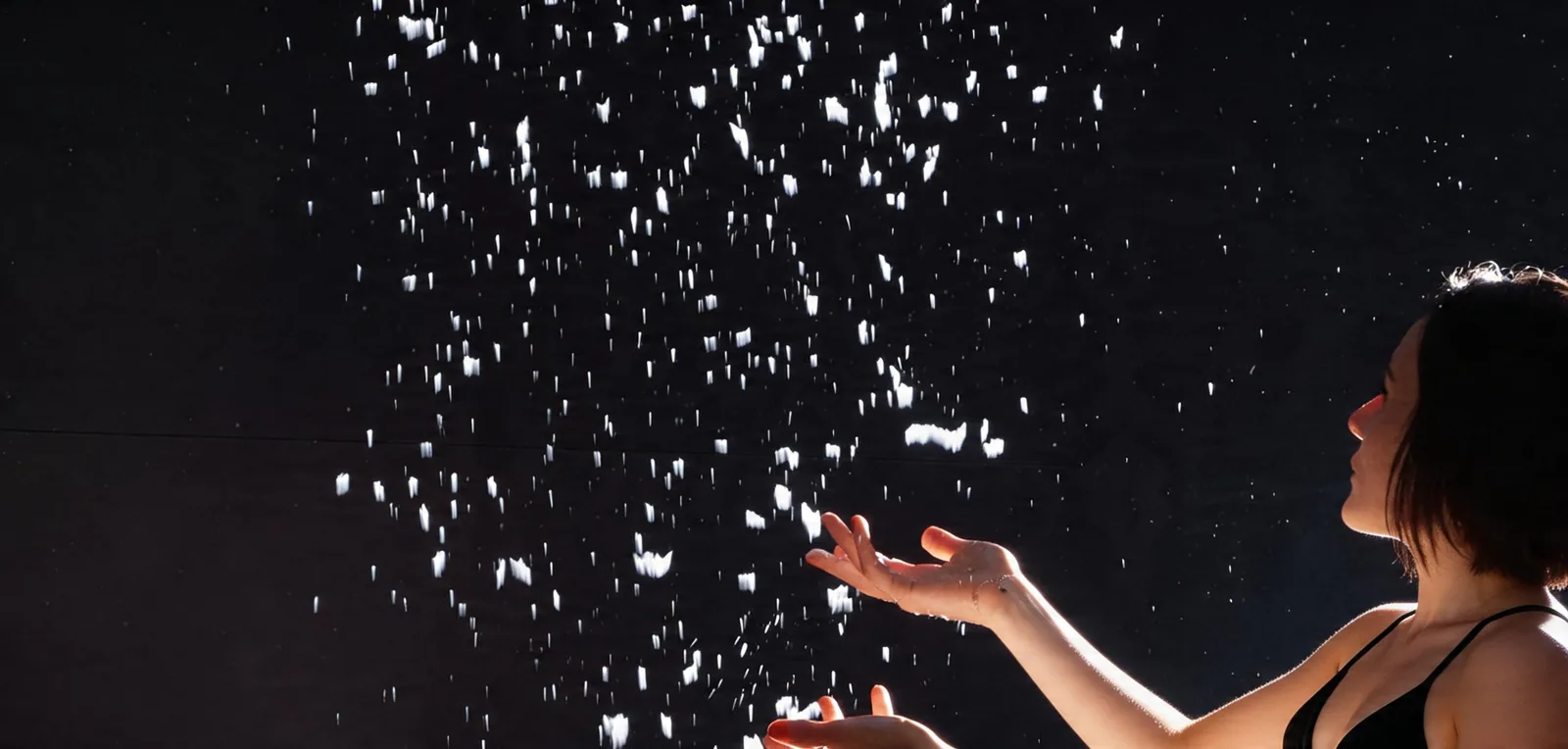 Femme recueillant dans ses mains ouvertes des flocons de neige tombant d'une douche de neige
